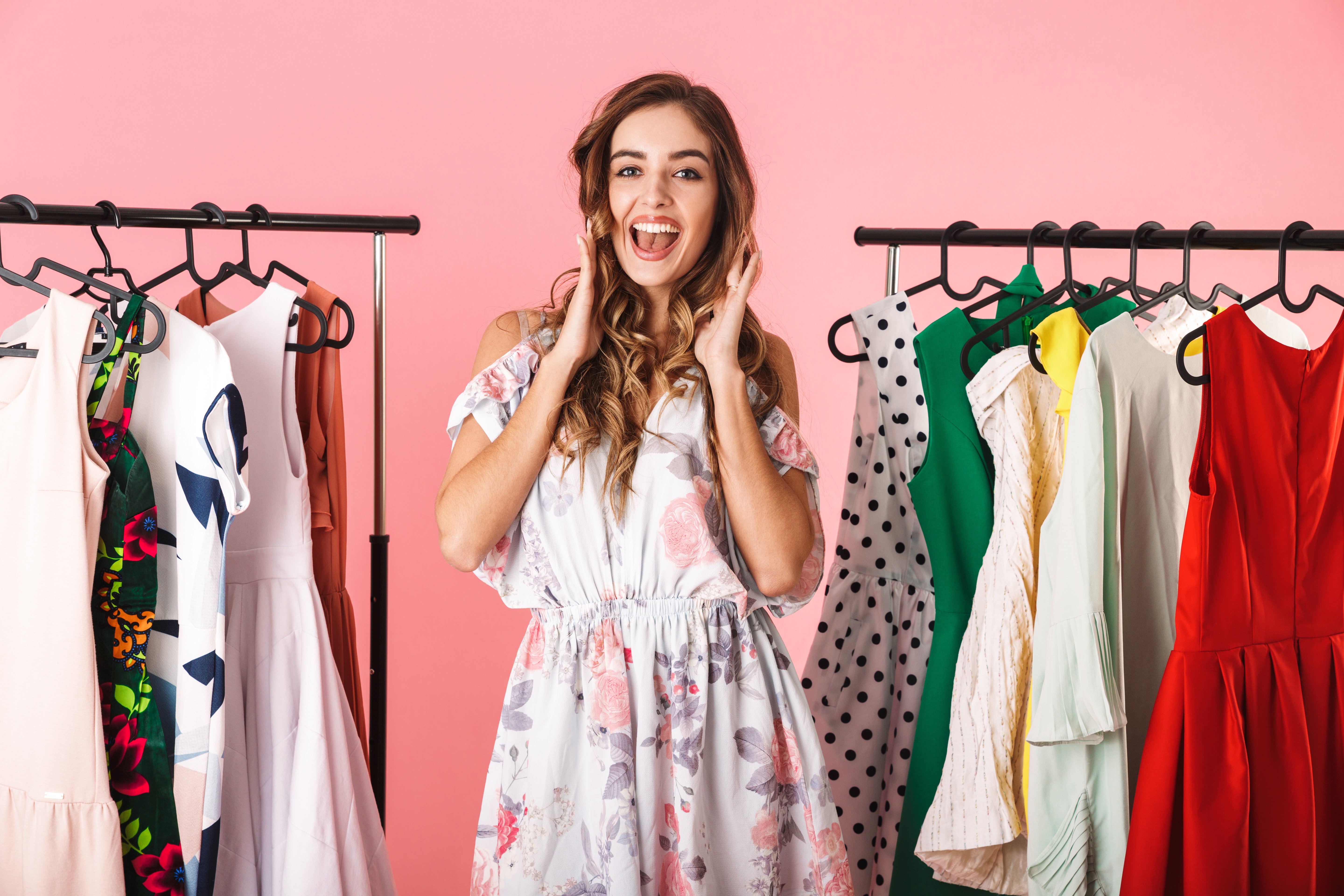 longitud-total-de-mujer-moderna-en-vestido-de-pie-cerca-del-armario-con-ropa-y-elegir-que-ponerse-aislado-en-rosa